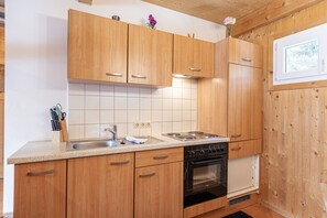 Eine Küche mit Holzausstattung, einem Herd, einem Backofen und einem Fenster.