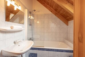 Un baño con lavamanos blanco, un espejo, ducha y bañera.