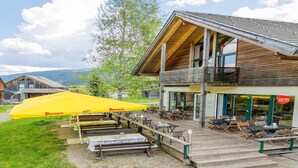 A wooden building with outdoor seating and a yellow umbrella. - Spacious chalet with wellness area (St. Georgen am Kreischberg)