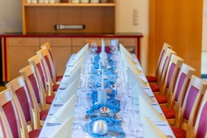 Une longue table à manger, entourée de chaises, préparée pour un repas.