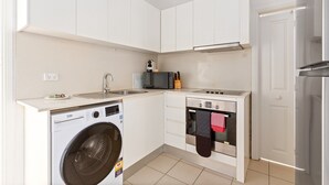 Een kleine keuken met een wasmachine, magnetron, oven en een koelkast.