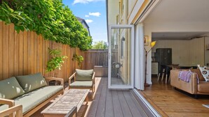 Un patio amplio con suelo de madera, un sofá, sillas y una zona de comedor.