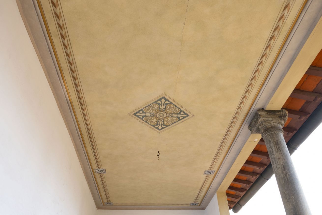 A ceiling with a decorative diamond pattern and a central cross symbol.