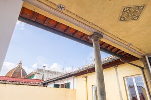 A building with a yellow facade, a tiled roof, and a dome structure in the background. - Duomo Sky Terrace Apartment (Florence)