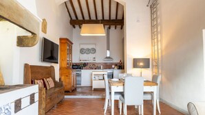 Una sala de estar acogedora con un banco de madera, una mesa de comedor con sillas, una cocina al fondo y un ventanal con vistas.