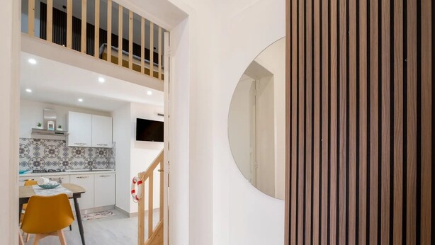 En modern inredning med ett kök, ett matområde och en trappa som leder upp till ett loft.