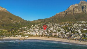 A coastal town with a beach, residential buildings, and a prominent mountain. - Luxury villa 120m from beach & restaurants striking ocean & mountain view-by JGM (Cape Town)