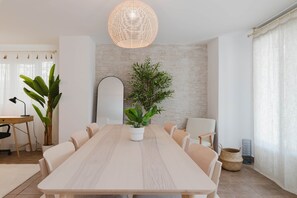 A modern dining room with a long table, chairs, a potted plant, and a hanging light fixture. - House with Barbecue Pool and Private Parking - Zona norte playa Gandía (Gandia)