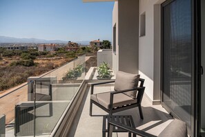 A balcony with a chair and potted plants, overlooking a residential area with mountains in the distance. - Sav & Leo Mindful Residences, Villa Sav (Crete, Greece.)