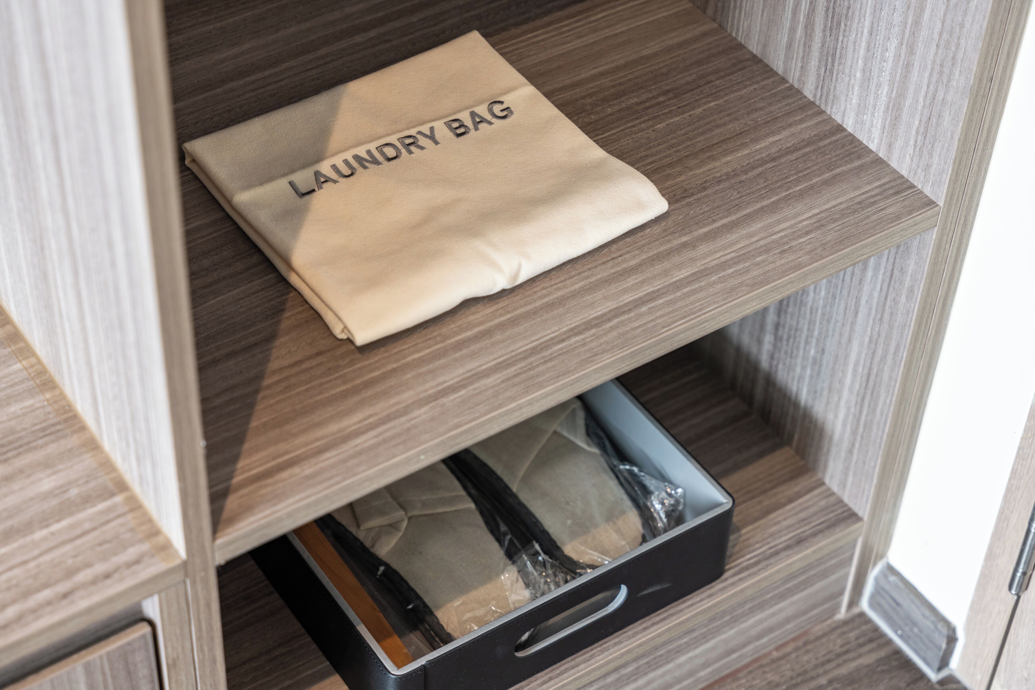 A neatly folded laundry bag labeled 'LAUNDRY BAG' on a wooden shelf.