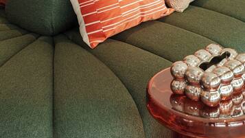 A green tufted ottoman with a round side table beside it, featuring a decorative metal object.