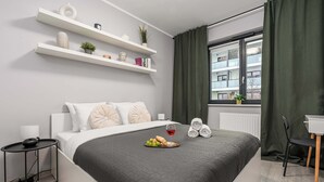 Un dormitorio moderno con cama, mesita de noche y ventana con cortinas.
