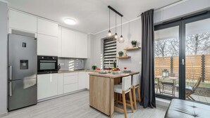 Una cocina moderna con una isla central, electrodomésticos integrados y un amplio ventanal corredera al exterior.