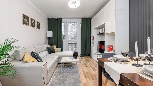 Ein modernes Wohnzimmer mit einer Couch, einem Couchtisch und einem Essbereich mit Tisch, Stühlen und einem Fernseher.