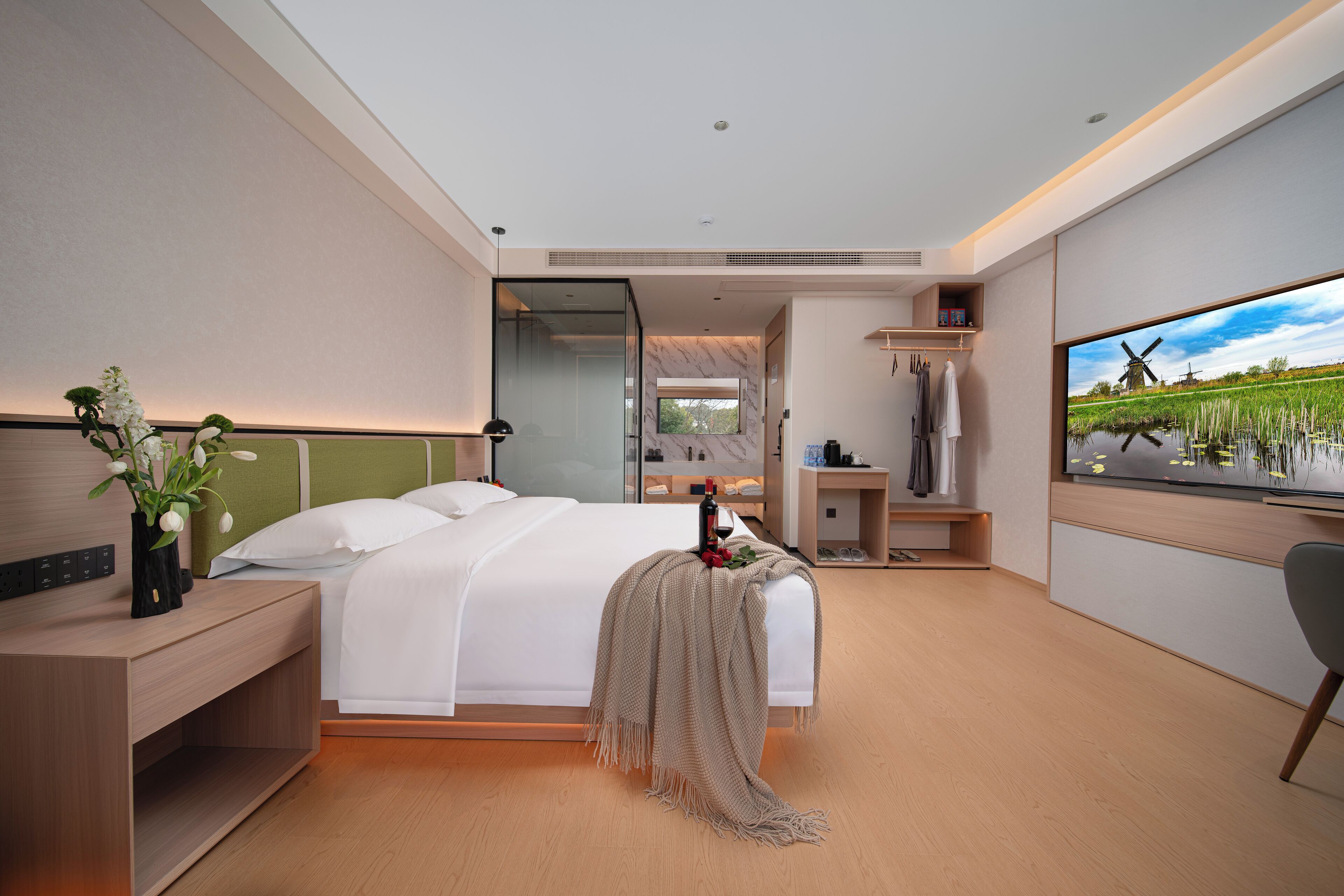 Una habitación de hotel moderna con cama, mesita de noche, televisión y ventana con vistas a un molino.