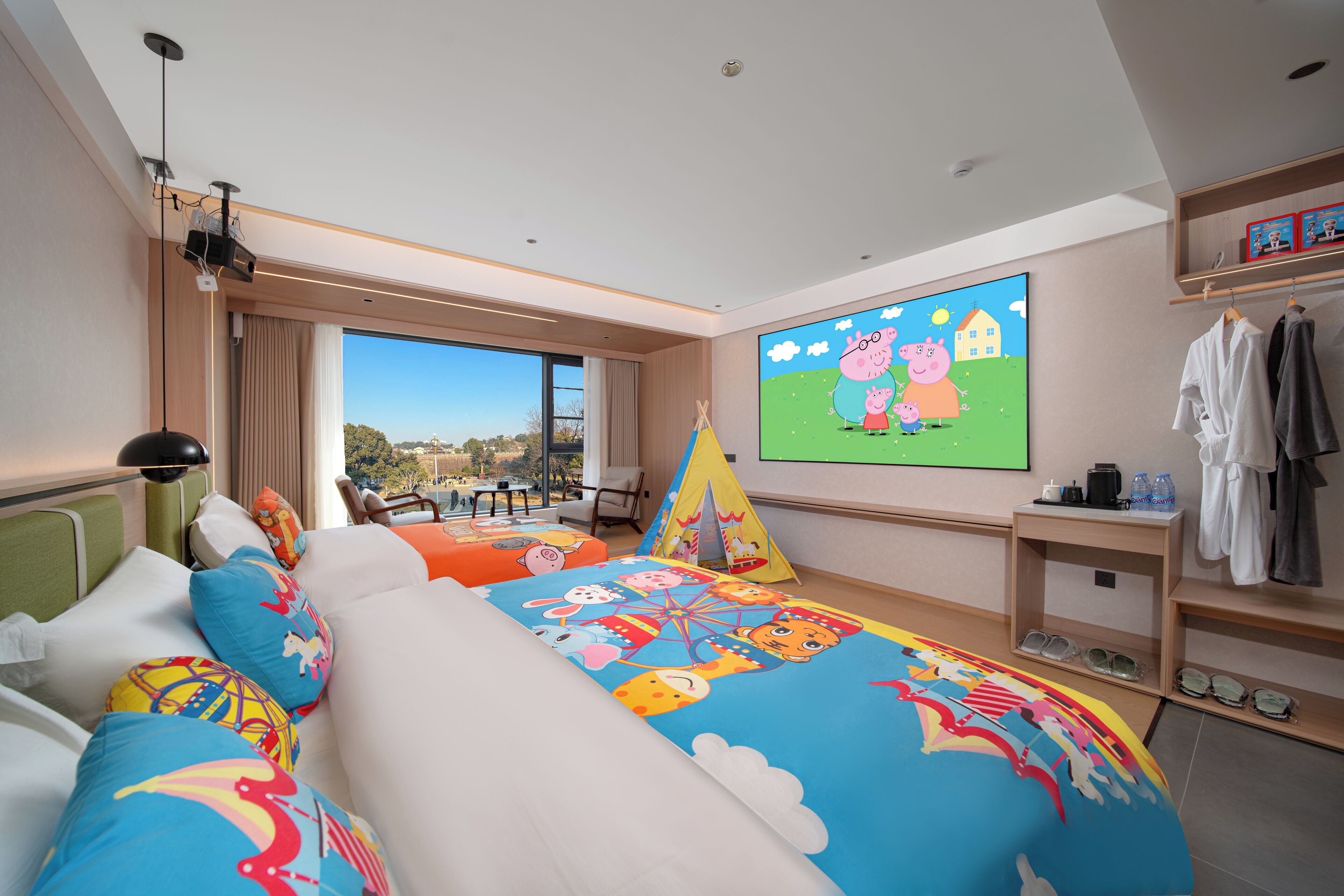 Habitación de hotel con una cama grande, una pantalla de televisión, un ventanal con vistas y una mesita con una lámpara.