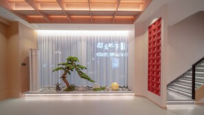 A modern interior with a minimalist design, featuring a central decorative tree, a staircase, and a red shelving unit. - She County Liuyue Qingshe Guesthouse  (Huangshan)