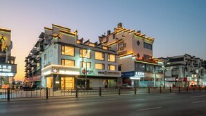 A multi-story building with commercial signage, a gated entrance, and a street view. - She County Liuyue Qingshe Guesthouse  (Huangshan)