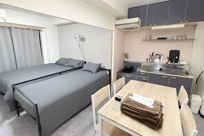 Habitació petita i senzilla amb un llit individual i una cuineta reduïda.