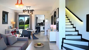 A modern living room with a sofa, dining area, and kitchen in the background. - Hydra House Nafplio (Mili)