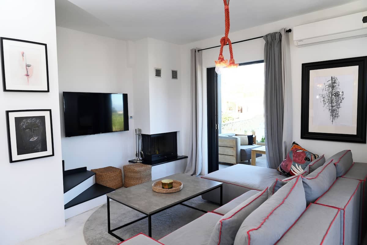 Un salon moderne avec un téléviseur à écran plat, un canapé, une table basse et des œuvres d’art accrochées aux murs.