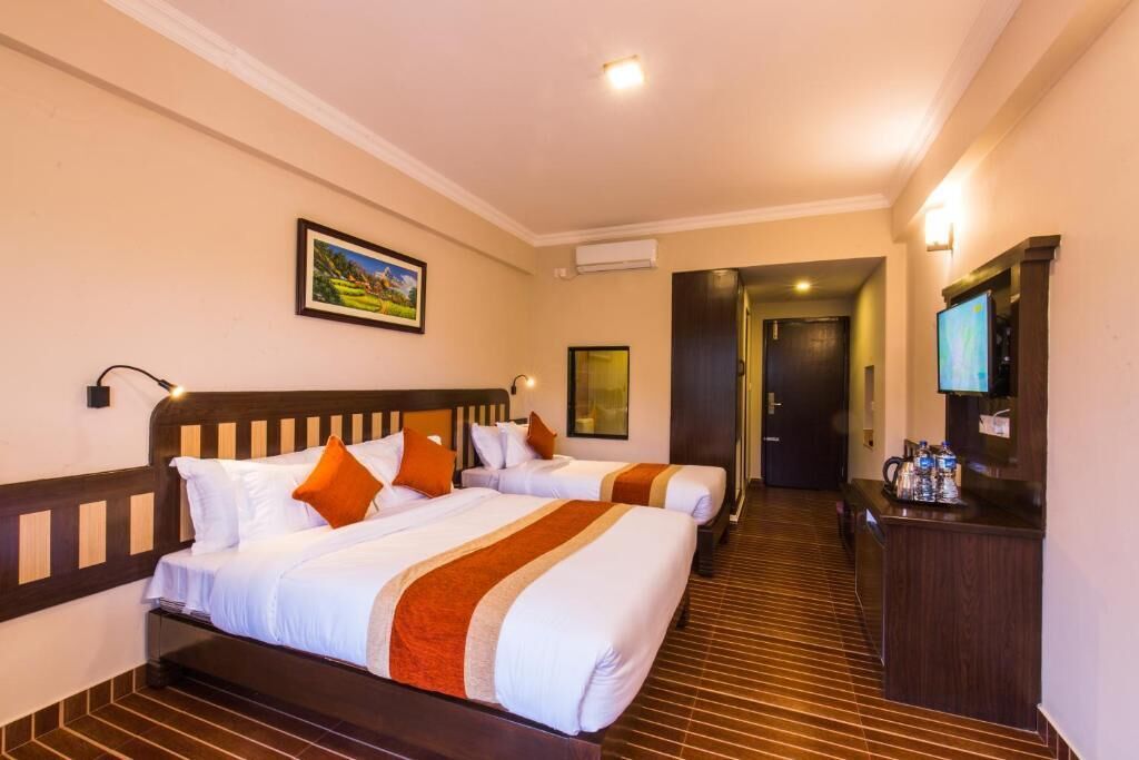 A hotel room with two beds, a desk, a television, and a picture on the wall.