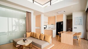 A modern living room with a sofa, coffee table, and dining area. - Elegant Aileen 3 Bedroom Pool Villa Naithon (Sa Khu)