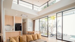 A modern living room with a sectional sofa, a round coffee table, and a dining area. - Elegant Aileen 3 Bedroom Pool Villa Naithon (Sa Khu)