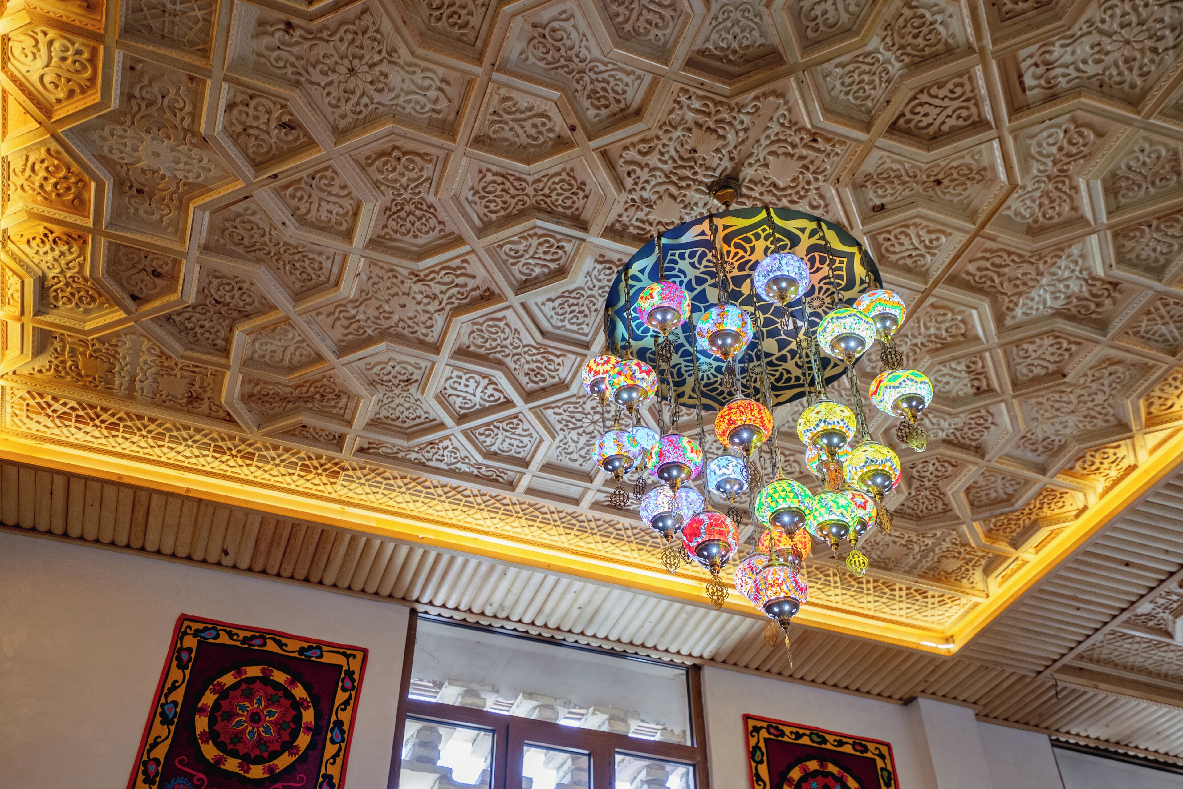 Eine Decke mit aufwendigen geometrischen Mustern und einem Kronleuchter mit bunten Glaskugeln.