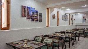 Un comedor con mesas y sillas, obras de arte en las paredes y una puerta que da a otra habitación.