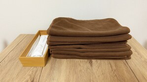 Een stapel bruine handdoeken in een houten dienblad op een houten tafel.