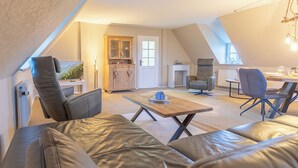 A cozy loft-style living space with a high ceiling, a dining area, and a seating area with leather sofas. - Vacation apartment "Elsabea" in Husum-Schobüll for up to 4 people (Husum)