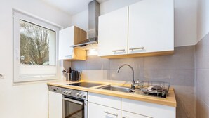 Een moderne keuken met witte kasten, een roestvrijstalen spoelbak en een inbouwoven.