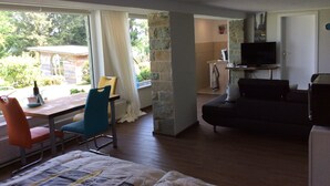 Una stanza con un letto, un tavolo con sedie, una televisione e un muro in pietra.