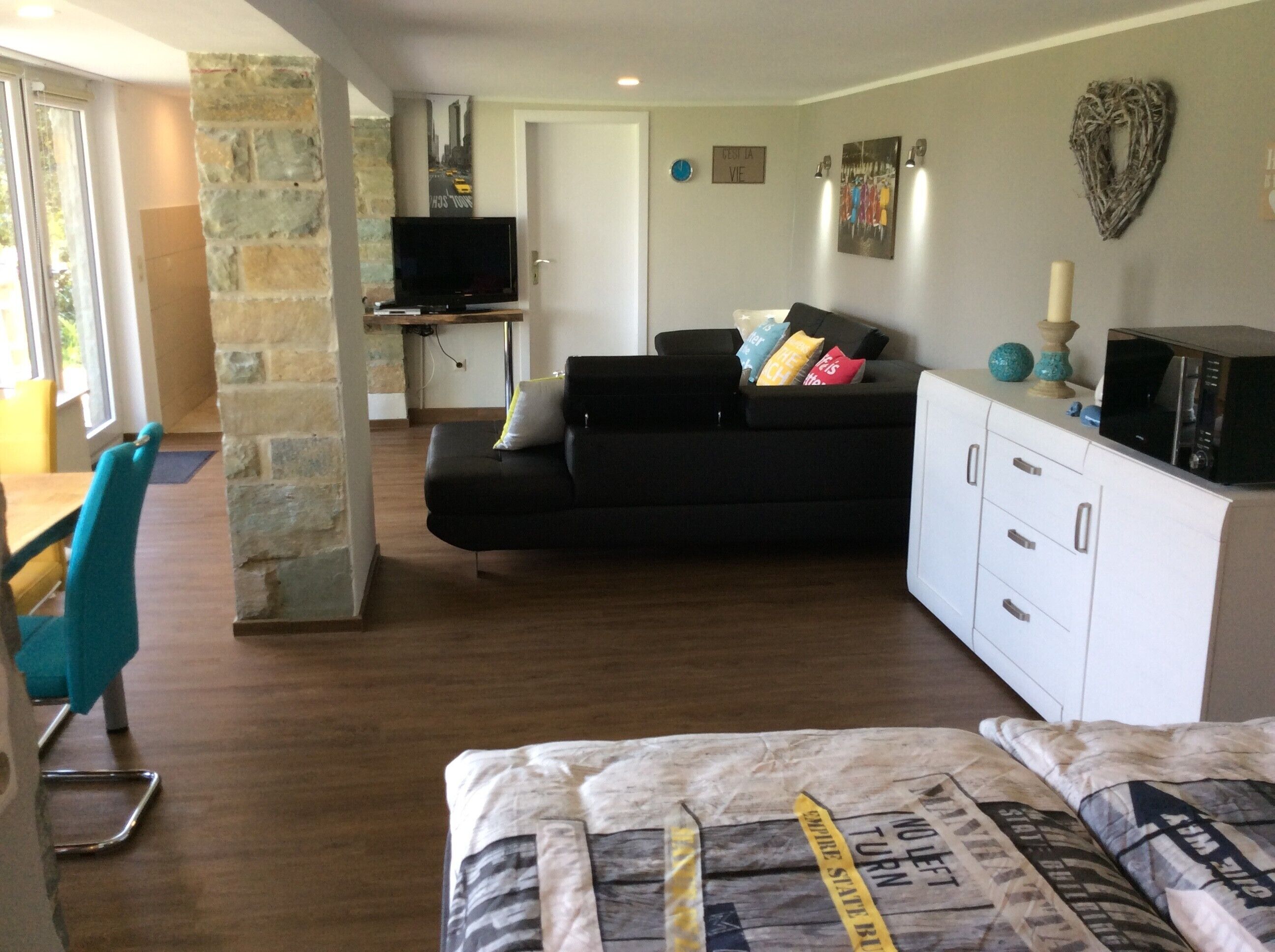 A living room with a sofa, a television, a white cabinet, and a bed.