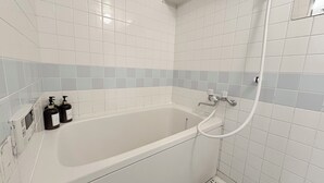 Un bagno moderno con una vasca, un soffione a mano e due flaconi di sapone.