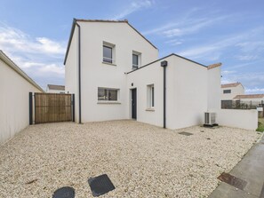 Ein modernes, zweistöckiges Haus mit Kiesweg, Holztor und einem kleinen Garten.