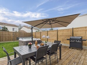 Eine Terrasse im Freien mit Esstisch, Whirlpool und Grill.