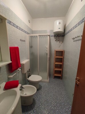 Pieni kylpyhuone, jossa on wc, bidee ja suihkukaappi.