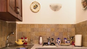 Une cuisine avec un plan de travail recouvert de carreaux, un évier, une cuisinière et divers ustensiles de cuisine disposés sur le comptoir.