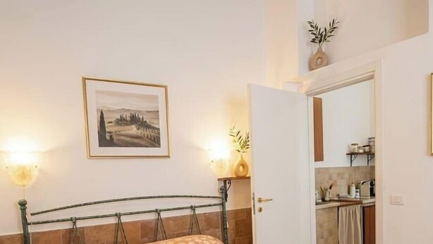 Un lit avec une couvre-lit à pois, une lampe de chevet et un tableau encadré au mur.