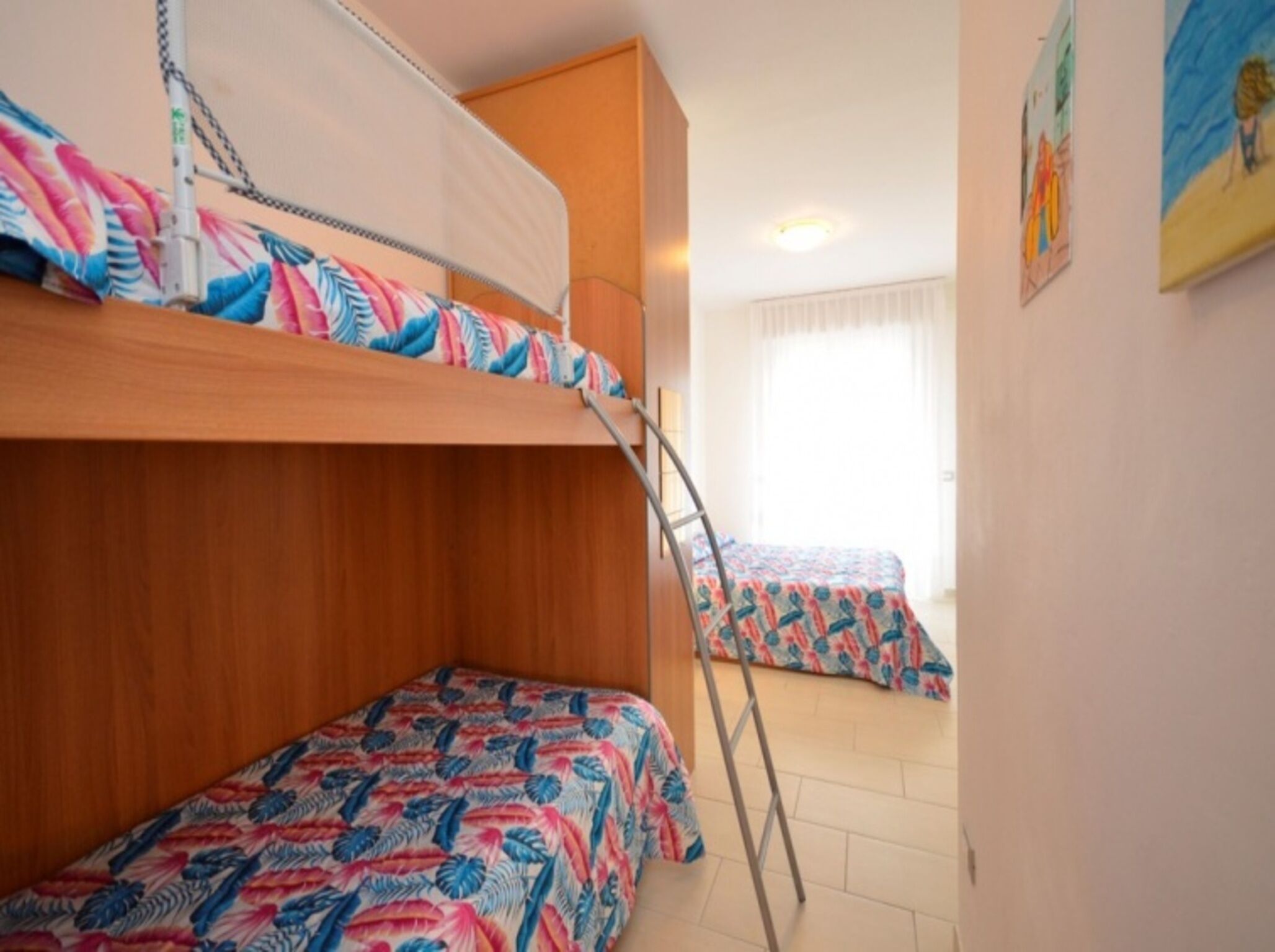 Une chambre de dortoir avec des lits superposés, une échelle et une fenêtre avec des rideaux.