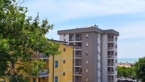 A multi-story residential building with balconies, a parking area, and a view of the beach. - House with seaview terrace - Beahost (Bibione)