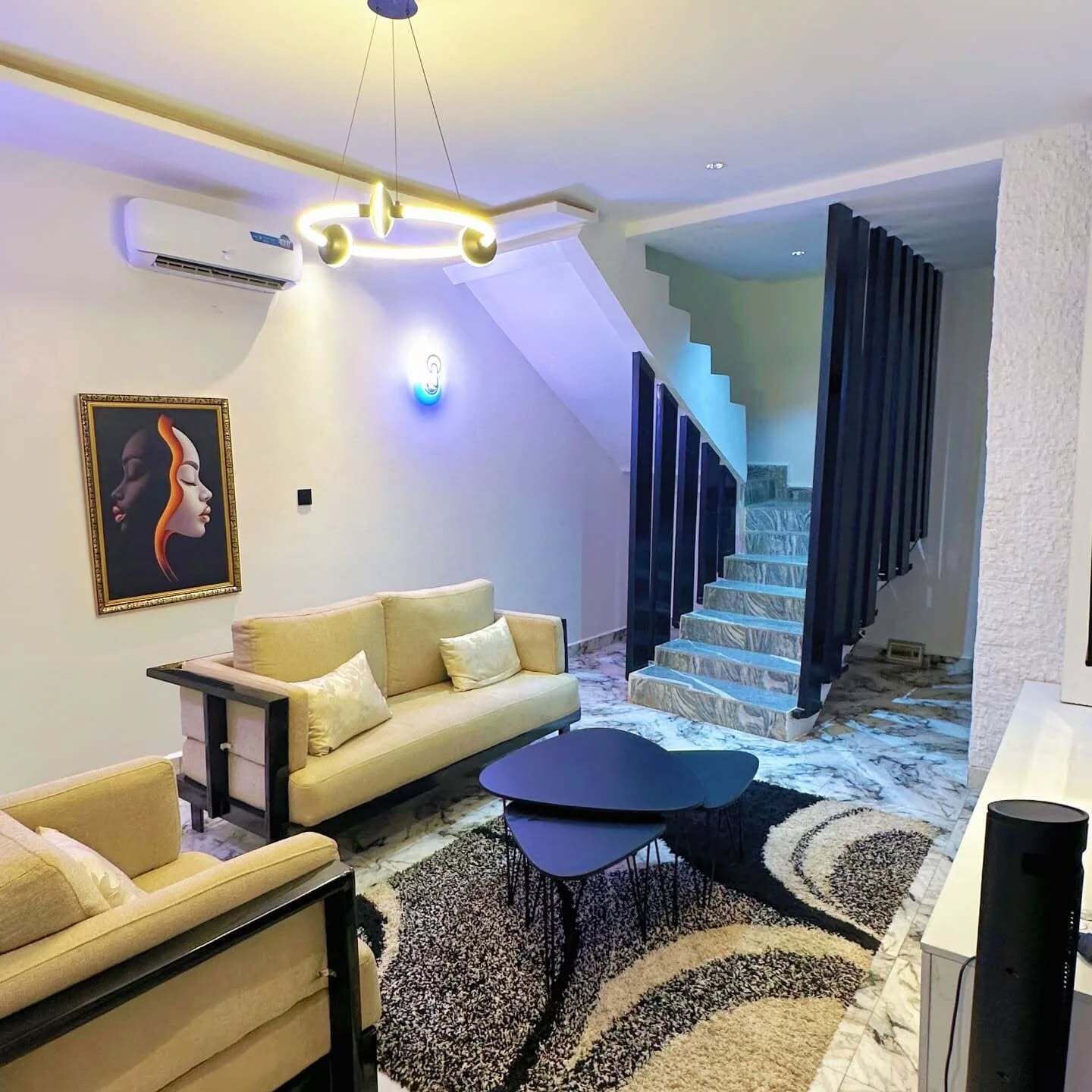 Un salon moderne avec un canapé, une table basse et un escalier menant à l’étage supérieur.
