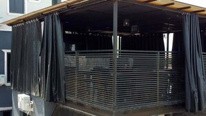 A covered outdoor area with a metal railing, a pull-down door, and potted plants. - Deroche Apartment (Abuja)