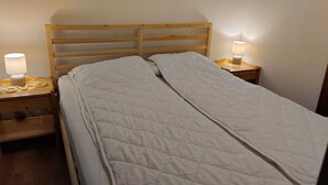 Uma cama de solteiro com cabeceira de madeira e duas mesas de cabeceira, cada uma com uma luminária.