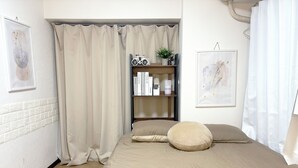 A bedroom with a bed, a bookshelf, a potted plant, and a framed picture on the wall. - XeroB HOUSE FLOLIA203 (Osaka, Naniwa Ward, Nanbanaka)