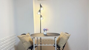 A corner room with a round table, two chairs, a vase with flowers, and a floor lamp. - XeroB HOUSE FLOLIA203 (Osaka, Naniwa Ward, Nanbanaka)