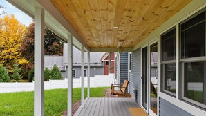 A covered porch with a swing chair, a wooden deck, and a view of the backyard. - Cozy 2-bedroom guest house in perfect South Hero with private lake access. (South Hero)