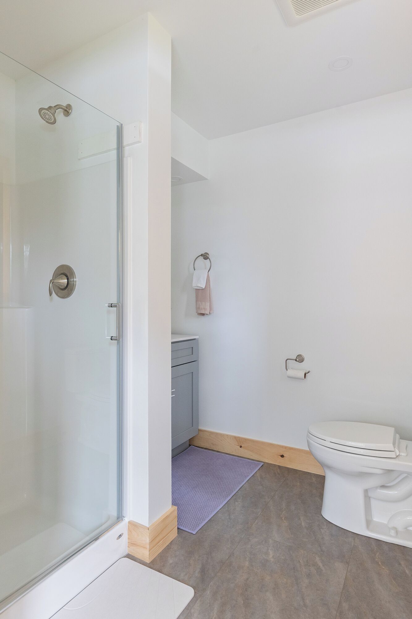A modern bathroom with a glass shower enclosure, a toilet, and a small sink area.
